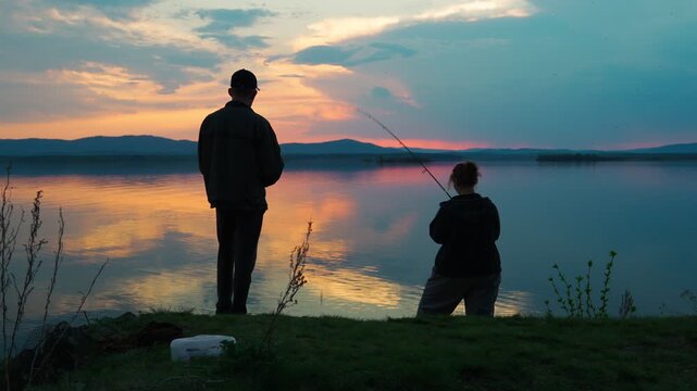 A young couple is fishing on a lake against the backdrop of an unusually beautiful sunset. Fishing and outdoor recreation. A healthy lifestyle. Real footage without staged elements.