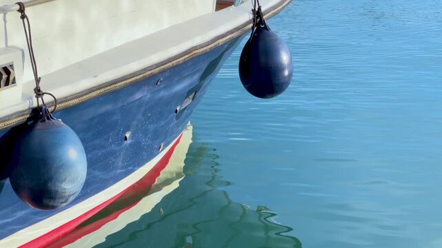 Blue Boat Hull and Fenders Floating in Calm Mediterranean Harbor Water