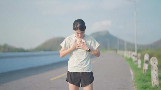 Adult runner suffering from acute chest pain and heart attack during running. Woman holding chest due to cardiac arrest, angina or heart disease. Sports medical and healthcare concept