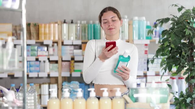 Girl in summer clothes scans code on medicinal mouthwash to check the expiration date. High quality 4k footage