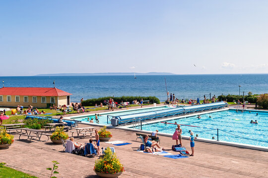 Crowded outdoor swimming pool by lake a sunny summer day