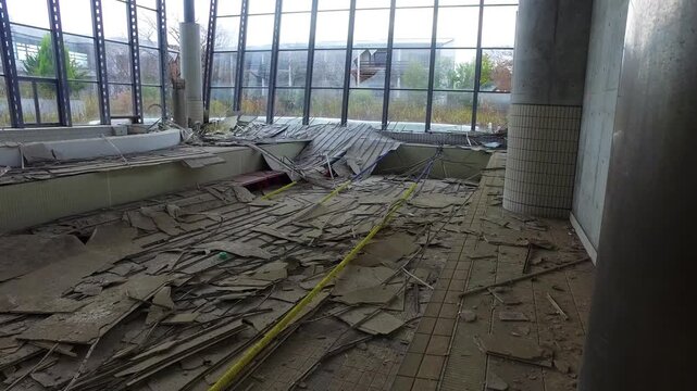 Melancholy pan across a ruined aquatic center filled with debris.