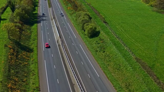 Passing through drone fly over four lanes and fast highway road in rural Mayenne with traffic, France