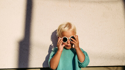 Smiling blond child wearing round sunglasses in warm sunlight. © Halfpoint