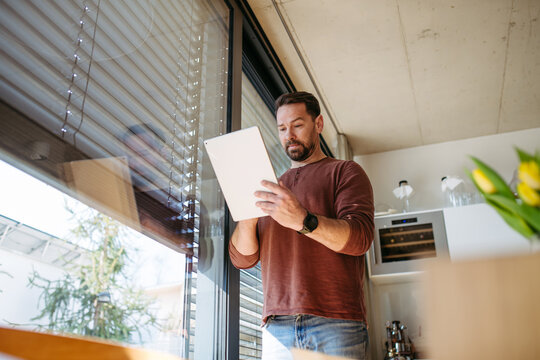 Man using smart home app to control electric window shades indoors.