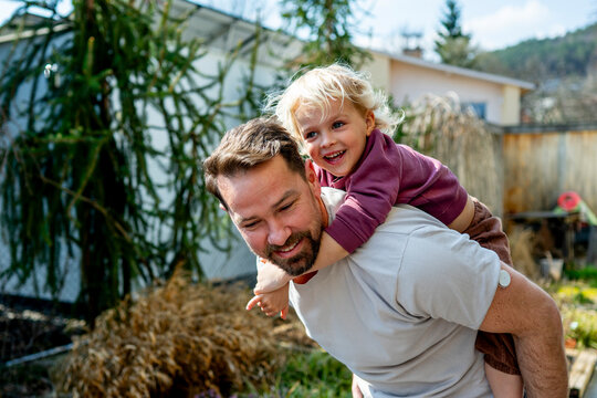 Diabetic dad enjoying playful moment with young son in backyard.