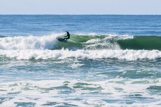 Surfer riding powerful ocean wave with wetsuit