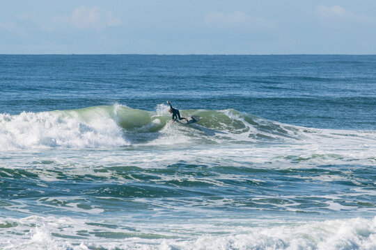Surfer wearing wetsuit riding a breaking wave in the vast ocean