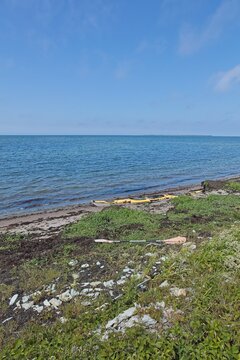 Abandoned yellow sea kayak rested on a sandy shore at Elda Pank (Elda cliff) in sunny summer weather, Saaremaa, Estonia, Europe.