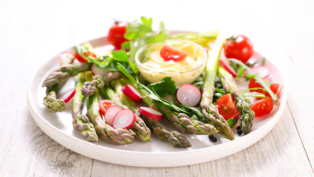 fresh green asparagus salad with radish and creamy dip on plate