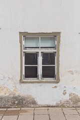 Fototapeta premium Traditional wooden casement window is set within a white stucco facade showing signs of age and deterioration, Saaremaa, Estonia, Europe.