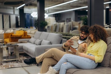 Fototapeta premium Young couple selecting sofa fabric in furniture store