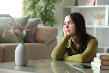 Obraz premium Serious young woman thinking at home looking away