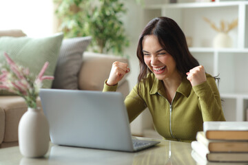 Excited young woman checking good news on personal computer © Antonioguillem