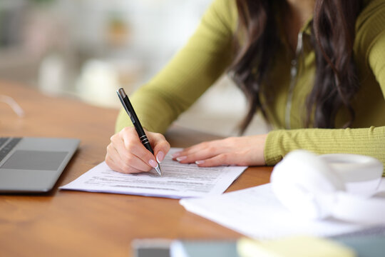 Student hands filling out form on a wooden table
