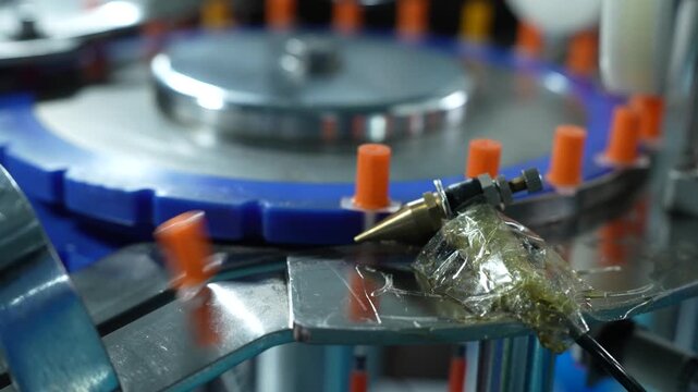 A close-up of disposable syringes sliding down a metal chute, mass production of disposable syringes