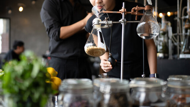 Close up Perfumers Creating Fragrance in Modern Laboratory with Botanical Ingredients and Glass Distillation Equipment