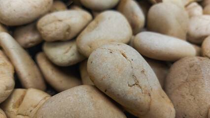 Obraz premium Macro Close Up of Smooth Beige River Pebble Stones with Natural Texture and Cracks Ideal for Spa Wellness and Stone Texture Background.