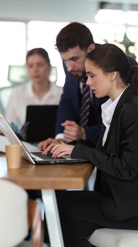 Experienced male employee helps a female employee make edits to spreadsheets. Employees working on the project in office. High quality 4k footage