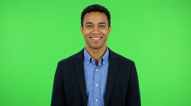 Successful businessman in a dark navy suit jacket smiling confidently at camera on a green screen background for corporate leadership videos financial consulting and executive profile interviews.