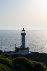 Fototapeta premium Tall White Lighthouse on a Lush Coastal Hill in South Korea