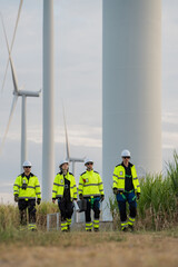 Fototapeta premium Team of professional engineers walking and inspecting wind turbine farm for renewable energy development.
