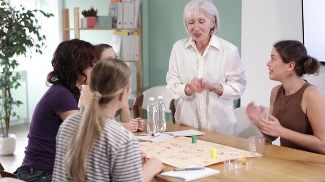 Focused female participants of different ages playing tabletop game in classroom