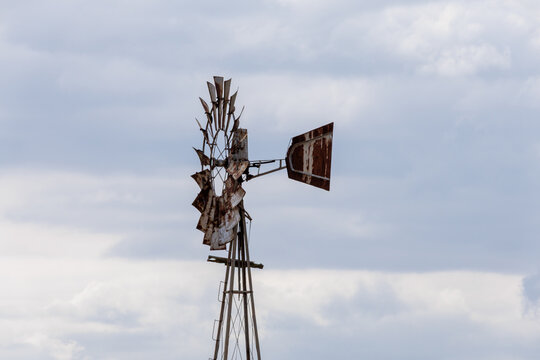 Rusty old windmill in rural landscape with clouds