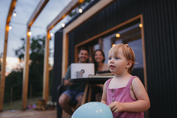 Naklejka premium Modern family spending time together on patio, father using laptop.