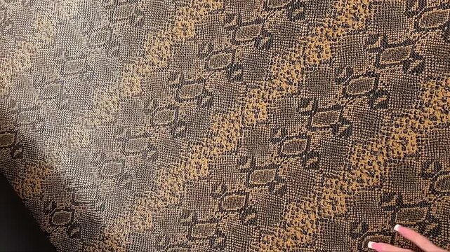 An exotic brown snakeskin faux leather material features a textured animal print and a black felt backing suitable for statement fashion apparel handbags and upholstery projects