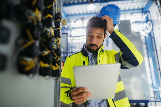 Industrial worker supervising machinery operations in modern production plant.