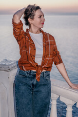 Obraz premium Woman sunset coastal Woman enjoying a serene evening on a terrace overlooking the ocean during golden hour while relaxing on summer vacation