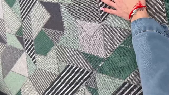 A heavy duty upholstery fabric features a dynamic grey and green geometric pattern with abstract triangles and stripes providing a modern textile solution for furniture and home decor