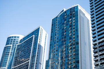 Fototapeta premium Modern high-rise residential buildings with glass facades against a clear blue sky.