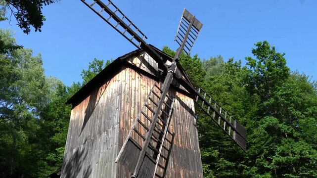 Old working windmill with wooden blades. Historical wooden structure with wind power. Flour grinding in ancient times.