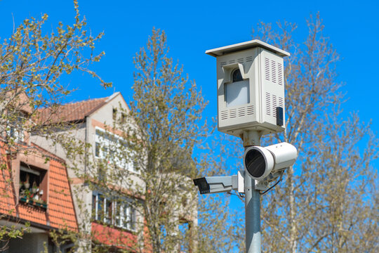 Traffic surveillance and speed enforcement cameras mounted on a pole overlooking a residential street, capturing vehicle and pedestrian movement for public safety and urban monitoring.