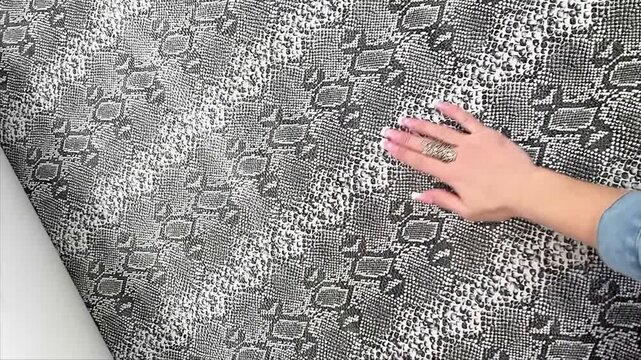 An exotic grey and white snakeskin faux leather material features a textured reptile scale finish and a black felt backing for fashion apparel handbags and luxury upholstery design