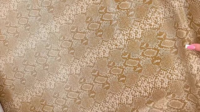 An exotic golden brown fabric displays a realistic snakeskin embossed pattern with a luxurious textured finish. This durable material is ideal for bold furniture upholstery and interior decor.