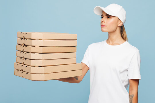 Delivery employee woman wear white cap T-shirt uniform workwear work as dealer courier hold pizza in cardboard flatbox isolated on plain pastel light blue background studio portrait. Service concept.