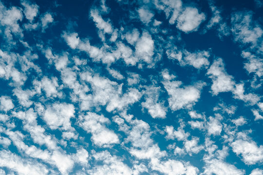Scattered white clouds against a bright blue sky