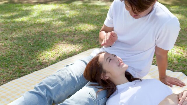 Young Asian Couple Relaxing on Picnic Blanket in Sunny Park