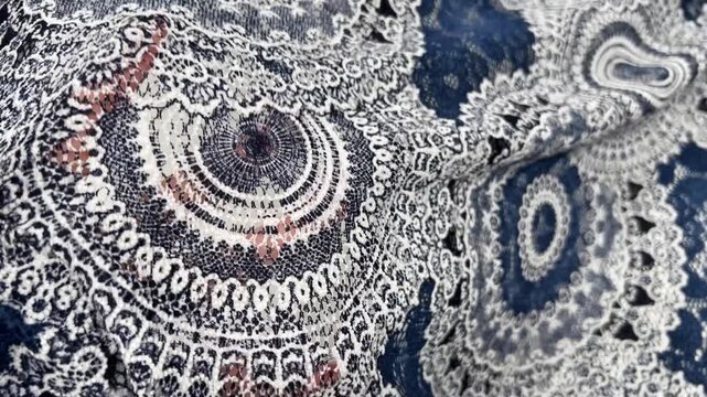 The elegant navy blue and white lace fabric features an intricate circular mandala pattern over a delicate mesh base. This lightweight decorative material is ideal for luxury fashion and overlays.