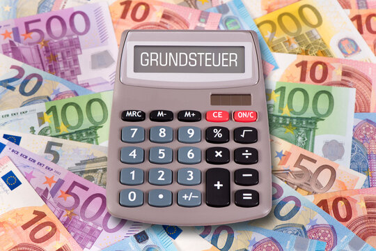 Ein Taschenrechner steht auf vielen Euroscheinen und im Display erscheint das Wort Grundsteuer - FOTOMONTAGE