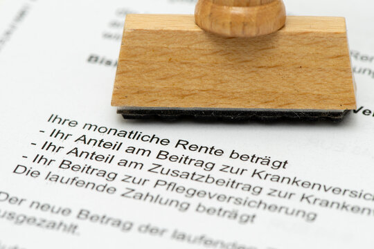 Ein Holzstempel mit Freiraum f&uuml;r individuellen Text steht auf einem Rentenbescheid - Symbolbild