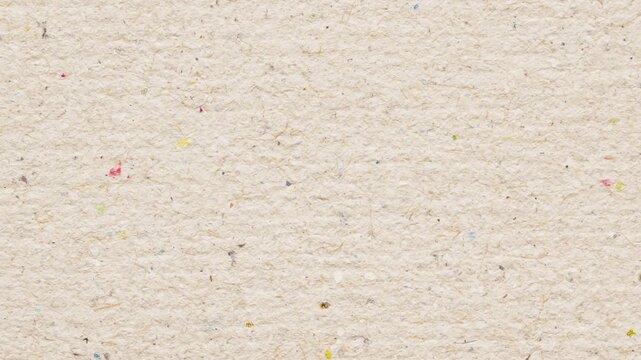 A close-up shot of a textured paper background with colorful flecks in an indoor setting from a neutral viewpoint with paper, texture, flecks, colors, and speckles.