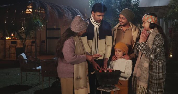 Indian happy mature adult female male speak share gossip enjoy cold winter have fun joy night outdoor garden place mom girl child kid talk with young man cook party food on barbecue spend quality time