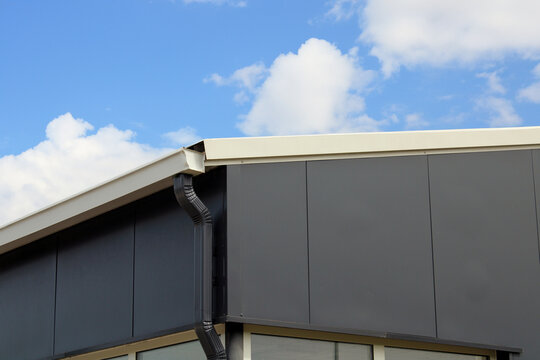 Goutti&egrave;re rectangulaire aluminium beige et descente gris anthracite sur le b&acirc;timent en bardage m&eacute;tallique