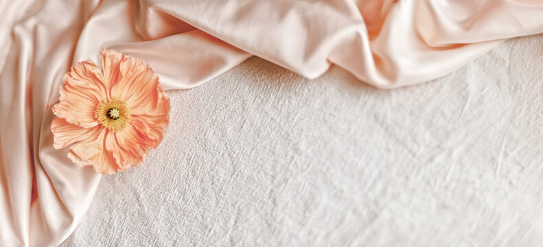 Peach Poppy on Pink Silk Draped over White Linen Flat Lay