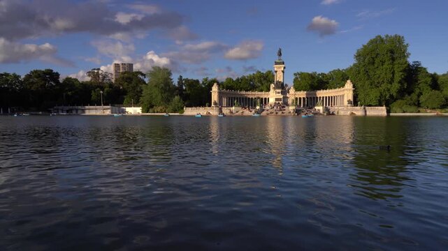Vista panor&aacute;mica del lago del Parque del Retiro de Madrid, con el Monumento a Alfonso XII al fondo, rodeado de &aacute;rboles y ambiente urbano.