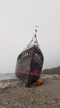 Abandoned Corpach Wreck ship grounded on shore in Scotland with rusted hull and overcast sky, vertical